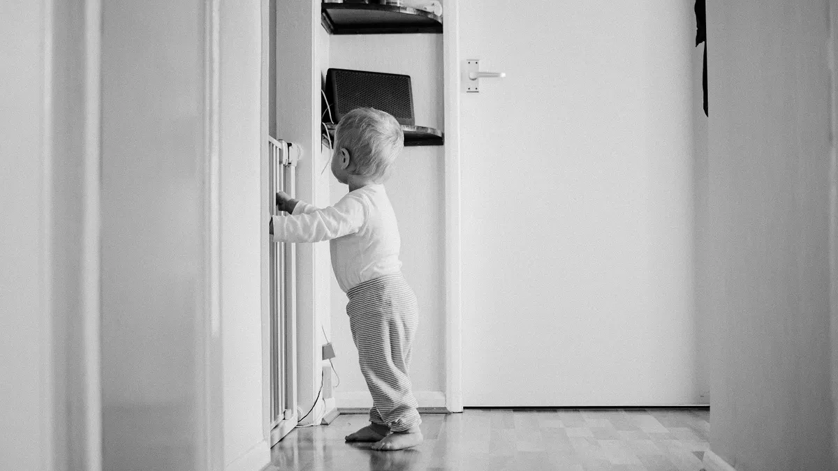 Toddler standing and holding onto furniture in a hallway