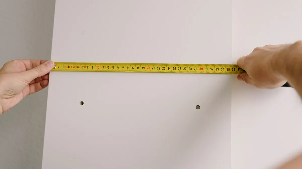 Hands measuring a wall with a tape measure